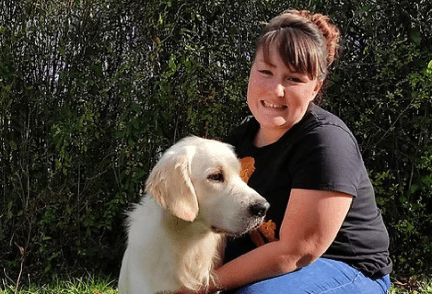 Un chien caressé par une femme souriante.