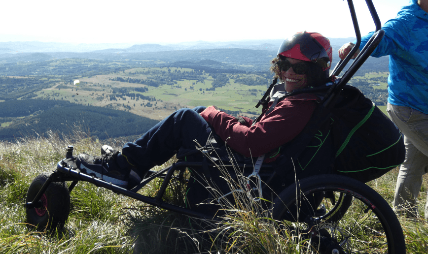 bénéficiaire de l'association trait d'union Auvergne Handis assise dans le fauteuil tout terrain à 3 roues de parapente au sommet du Puy-de-Dôme