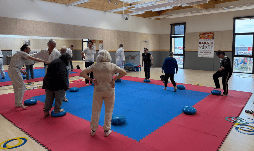 Découverte de para karaté adapté. Des personnes écoutent les consignes afin de s'initier en sécurité sur le tatami