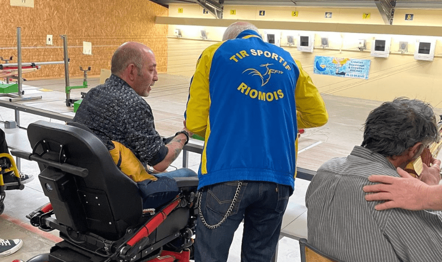 Un homme en fauteuil roulant électrique écoute les instruction d'un coach avant de s'initier au Paratir