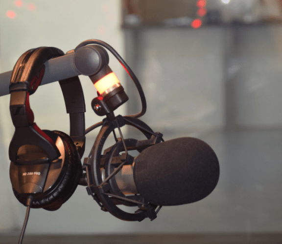Micro de studio d'enregistrement radio. Un casque audio est pausé sur le support du micro.